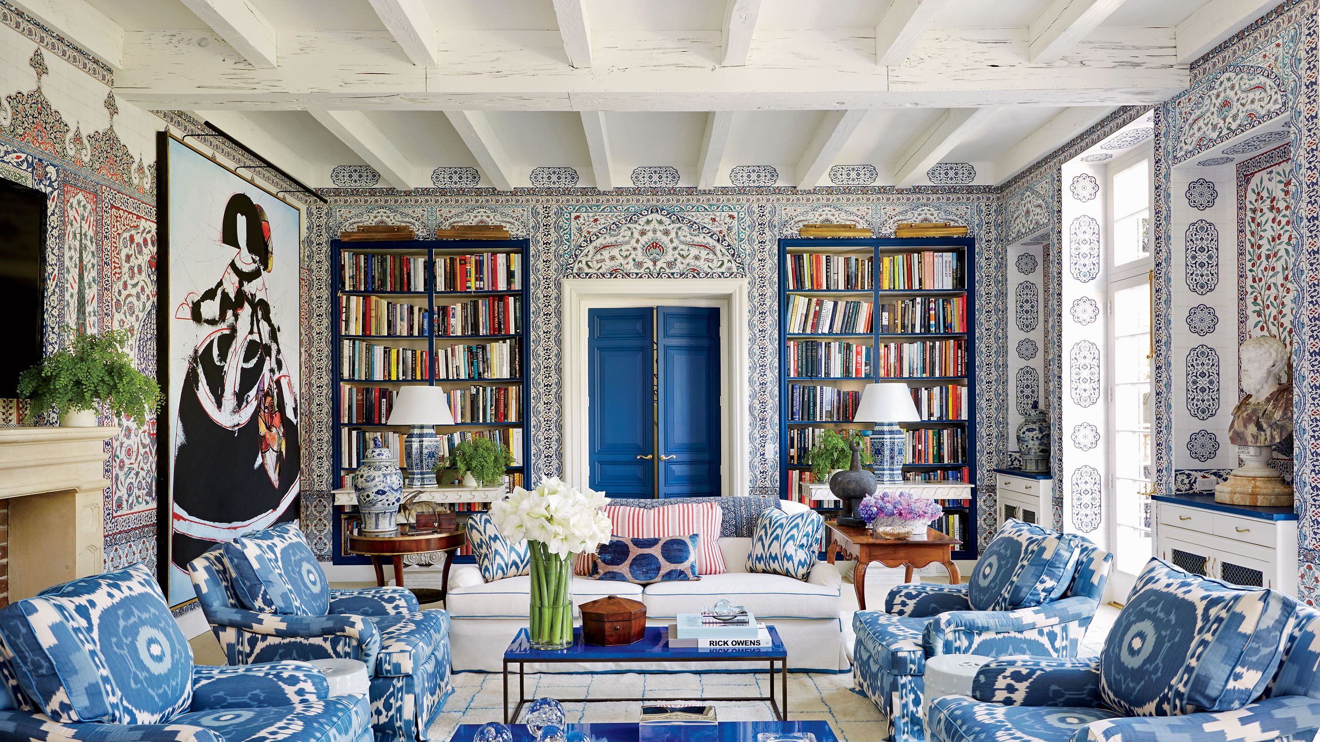 Sophisticated library interior with patterned wallpaper and blue built-ins