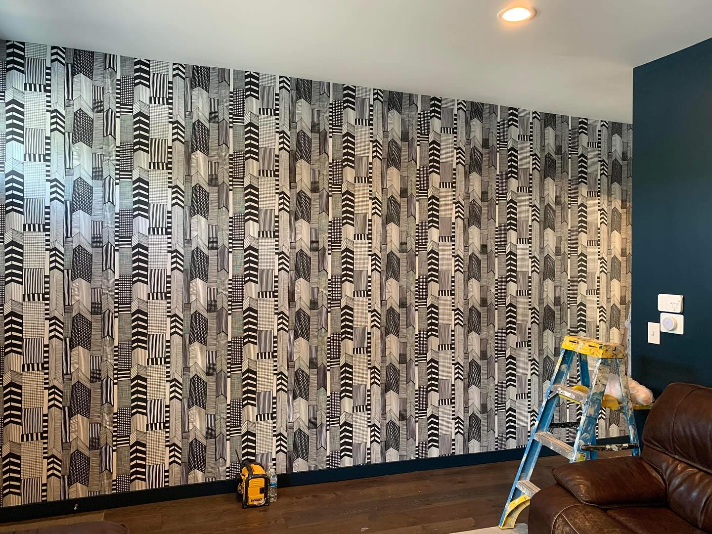 Black and ivory geometric wallpaper installation in a refined living room