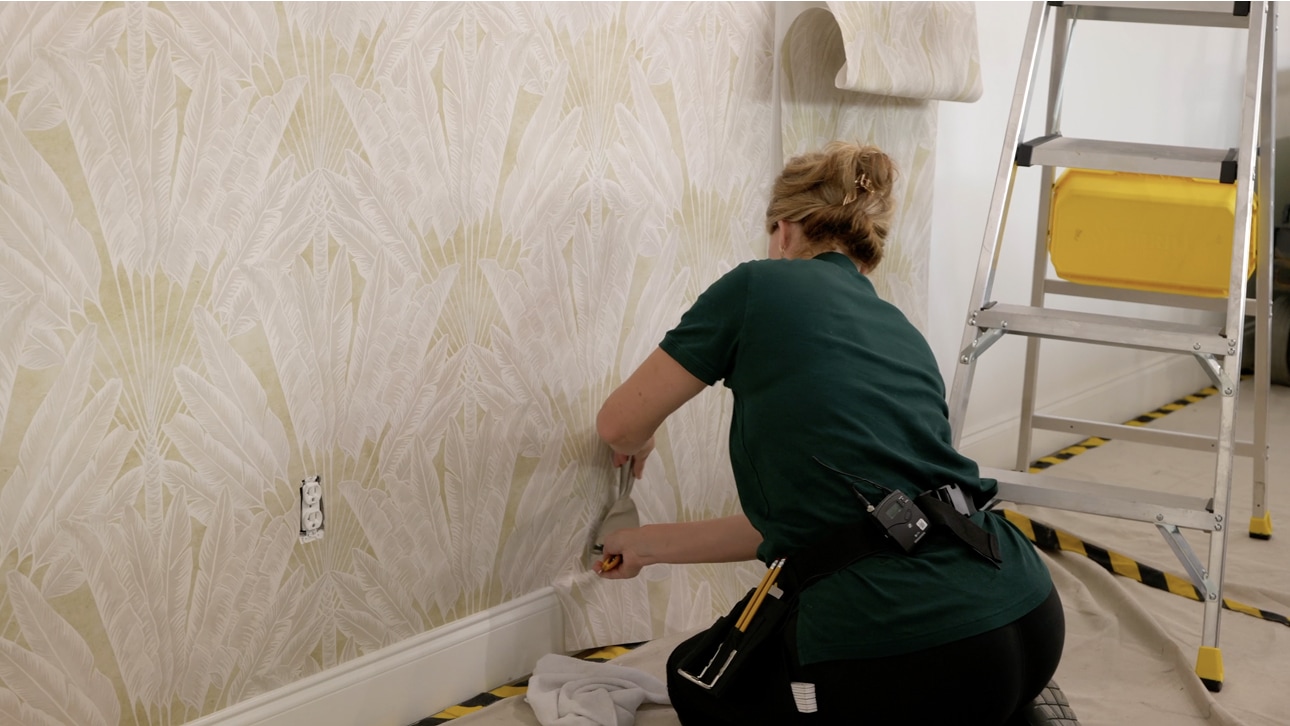 Professional wallpaper installer smoothing a patterned wallcovering